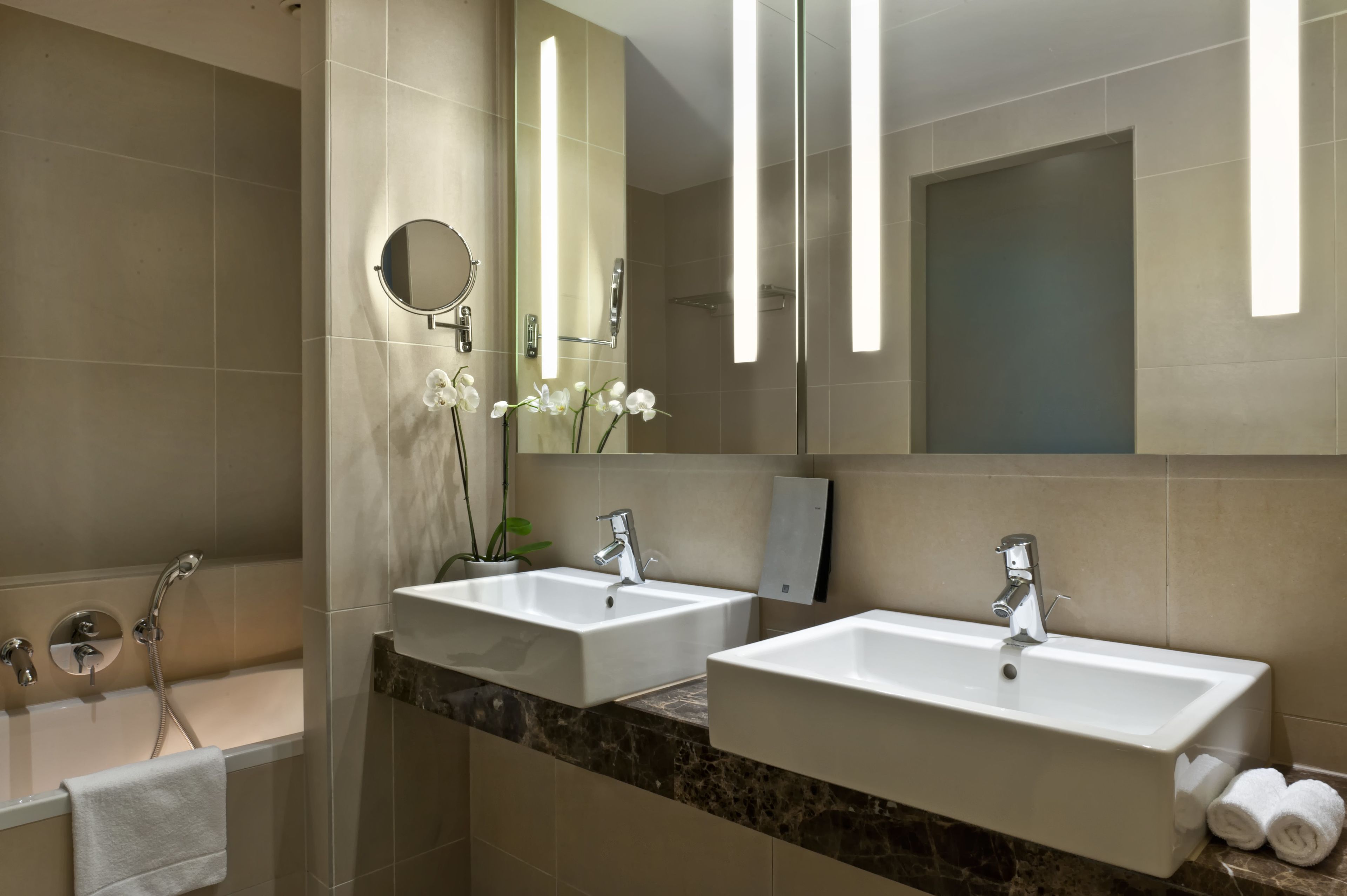Ein modernes Badezimmer mit zwei Waschbecken, einer Badewanne und einem großen Spiegel.