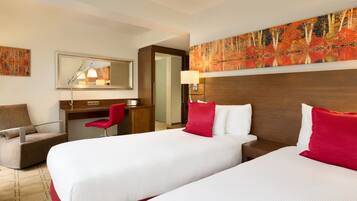 A hotel room with two beds, a desk, a chair, a mirror, and a painting on the wall.
