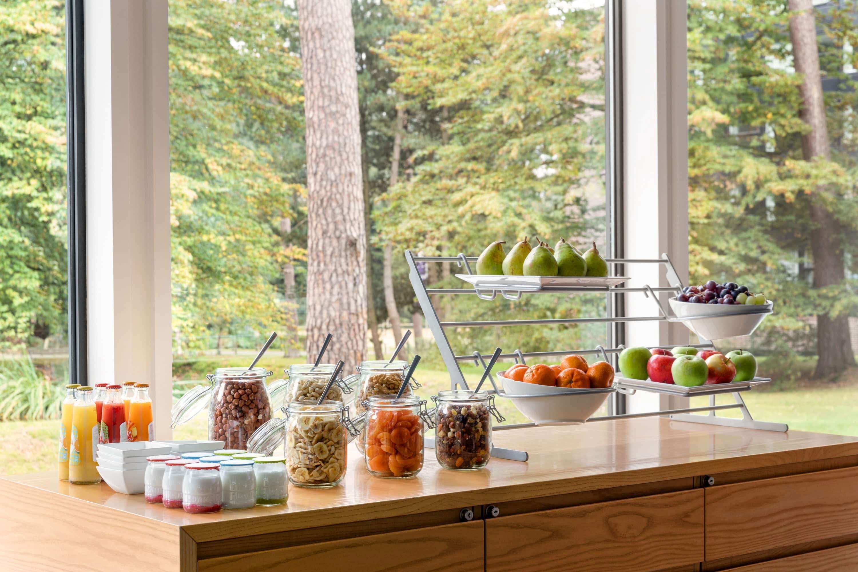 Un bufé de desayuno con diversas frutas, nueces y cereales.