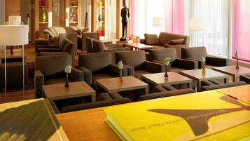 A hotel lobby with multiple seating areas, a statue, and a large window with curtains.
