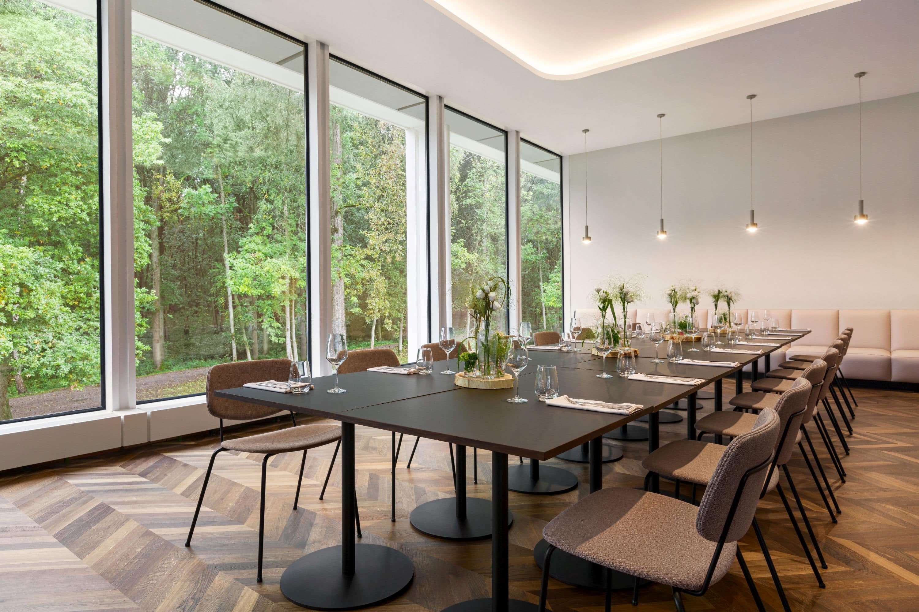 A modern conference room with large windows, a long table, and several chairs.