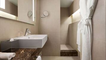 A modern bathroom with a marble countertop, a large sink, a mirror, and a white robe hanging on the wall.