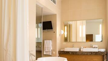 A modern bathroom with a freestanding bathtub, a large mirror, and a vanity with a sink and towel rack.