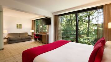 Habitación de hotel con una cama grande, un escritorio, un sofá y un televisor.