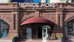 El exterior de un hotel con un letrero grande que dice "Черное море" y un logotipo encima.