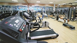 Un gimnasio con cintas de correr, máquinas de pesas y equipo de ejercicio.