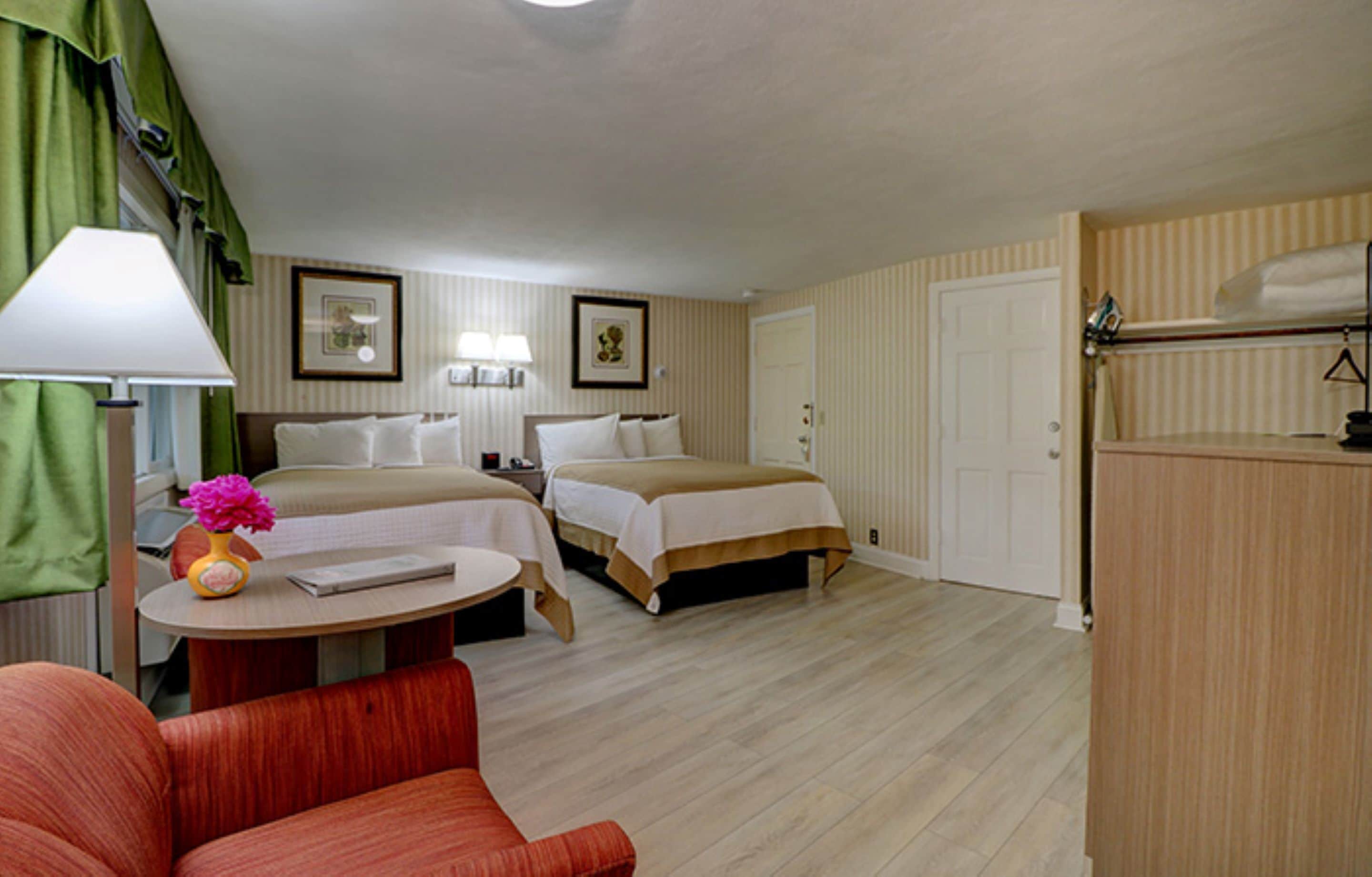 Ein Hotelzimmer mit zwei Betten, einem Schreibtisch mit Lampe, einem Stuhl und einem Schminktisch.