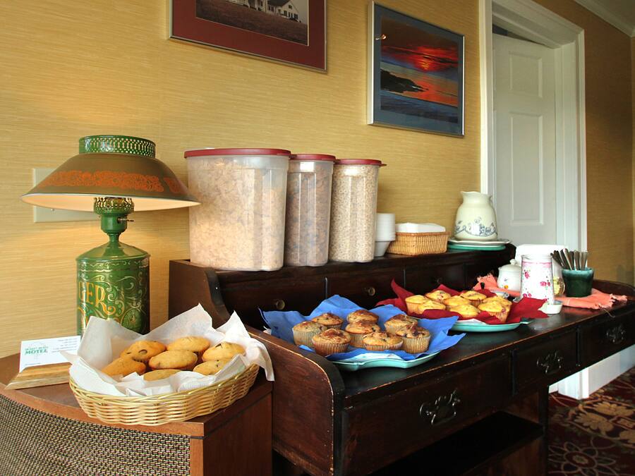 A breakfast buffet with pastries, a lamp, and storage containers on a wooden table.