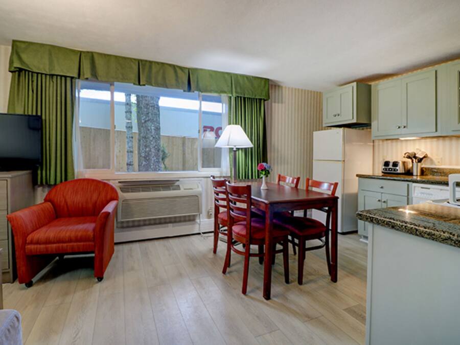 A compact living space with a dining area, kitchenette, and a television.
