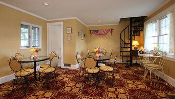 A dining area with a red carpet, a flag, and a spiral staircase.