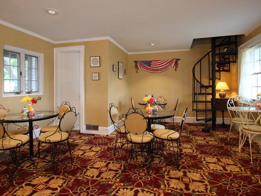 A dining area with a red carpet, a flag, and a spiral staircase.