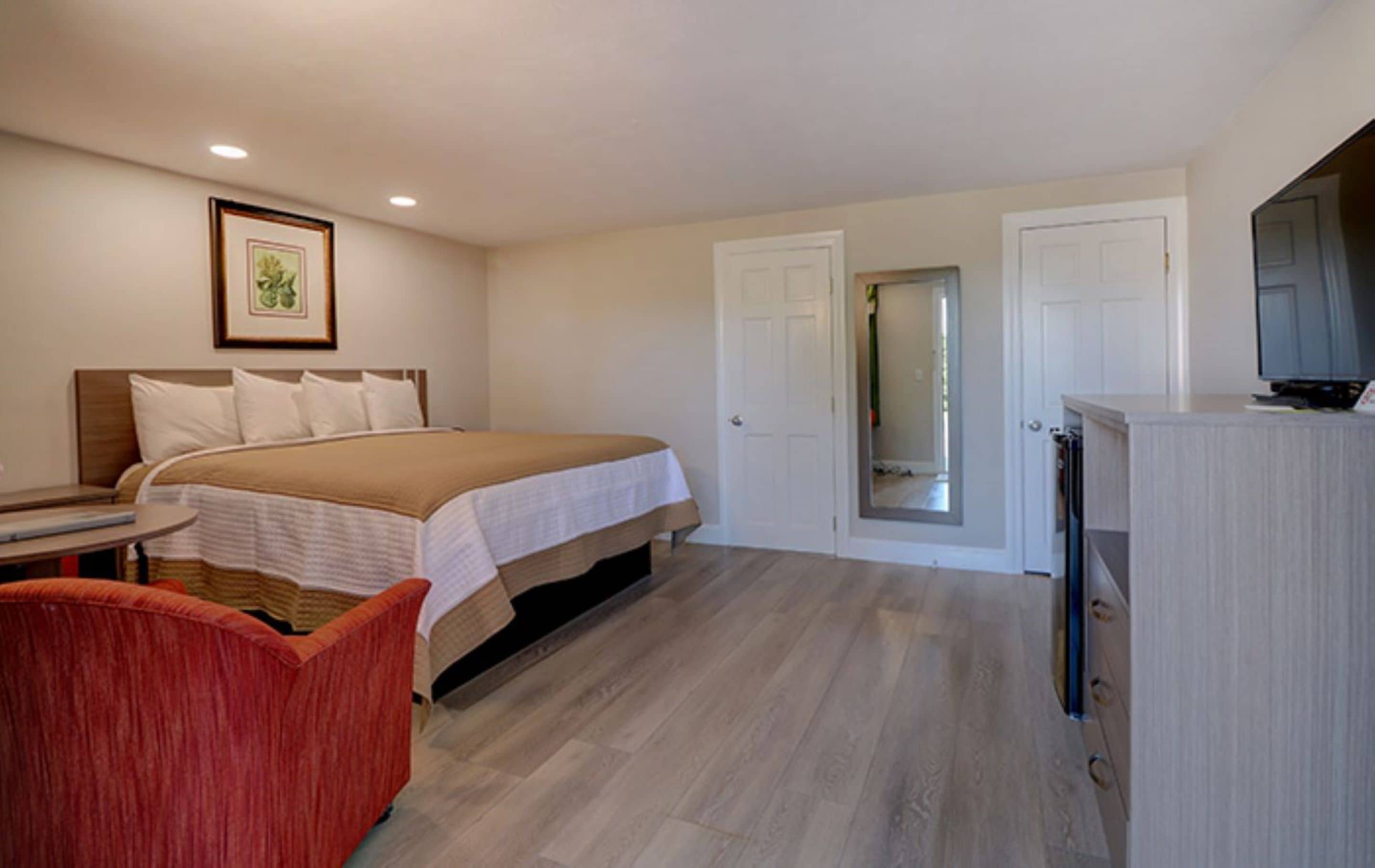 A hotel room with a bed, a TV, a desk, and a chair.