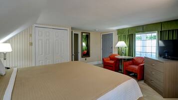 A hotel room with a large bed, a desk with a chair, a television, and a window with curtains.