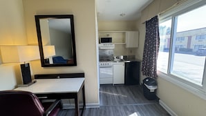 Habitación de hotel compacta con kitchenette, comedor y ventana grande.