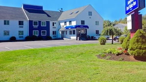 Un motel con toldo azul, un estacionamiento y un cartel que dice Americas Best Value Inn.