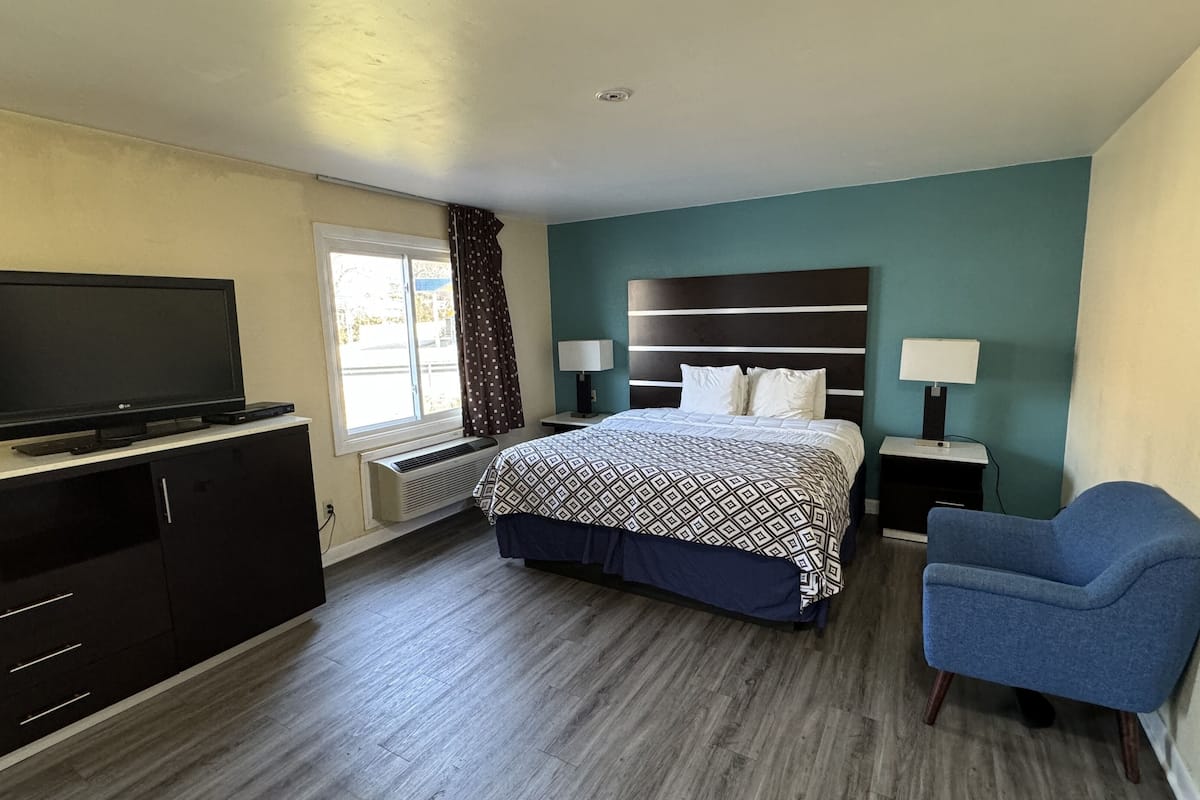 A hotel room with a bed, a TV, a desk, a chair, and a window.