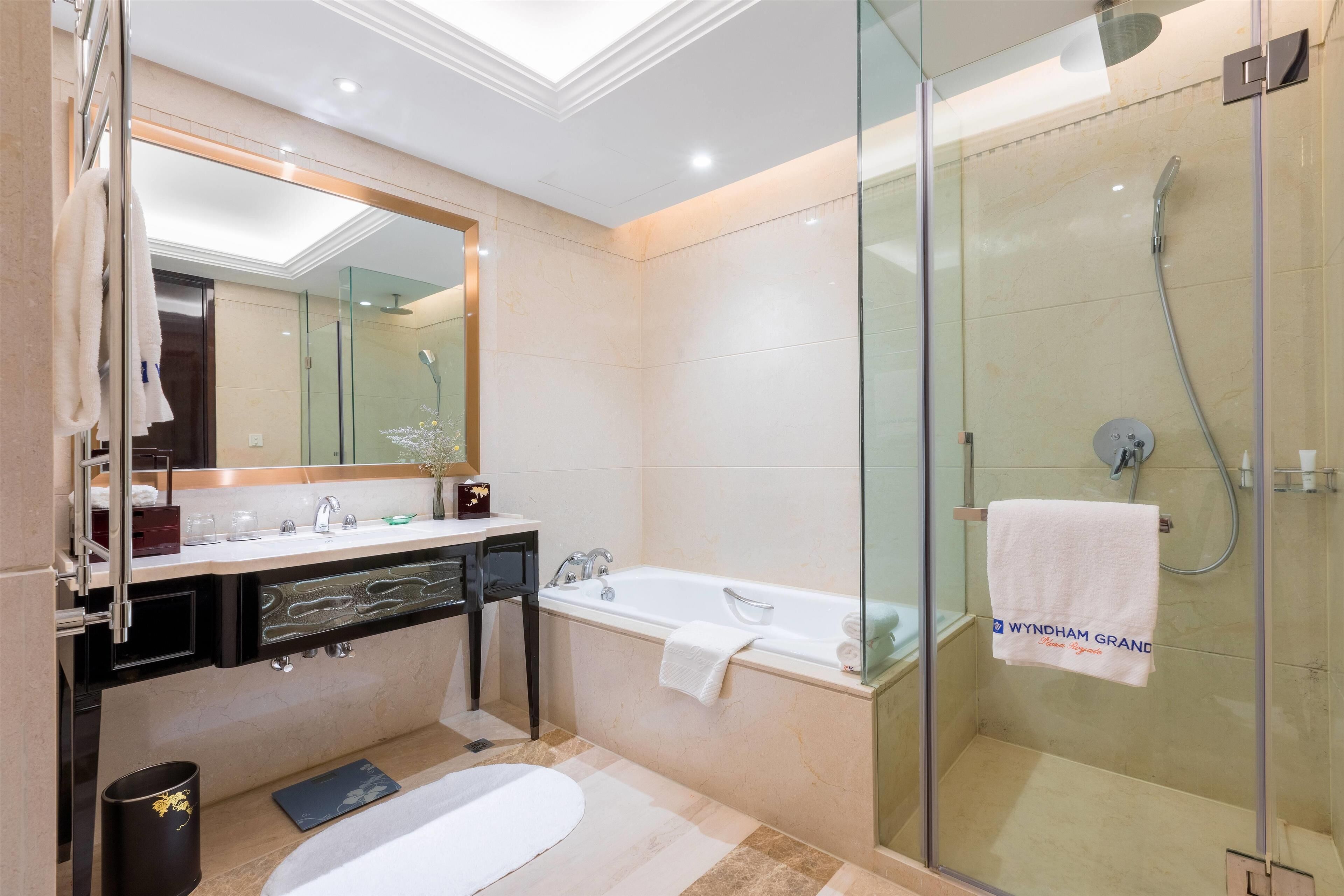 A modern bathroom with a glass-enclosed shower, a bathtub, and a vanity with a mirror.