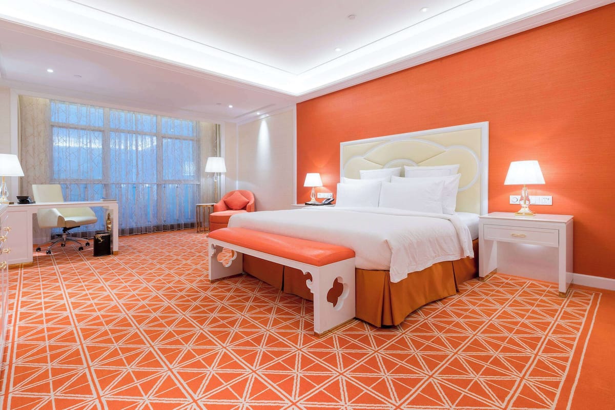 A hotel room with a large bed, a desk, and a chair.