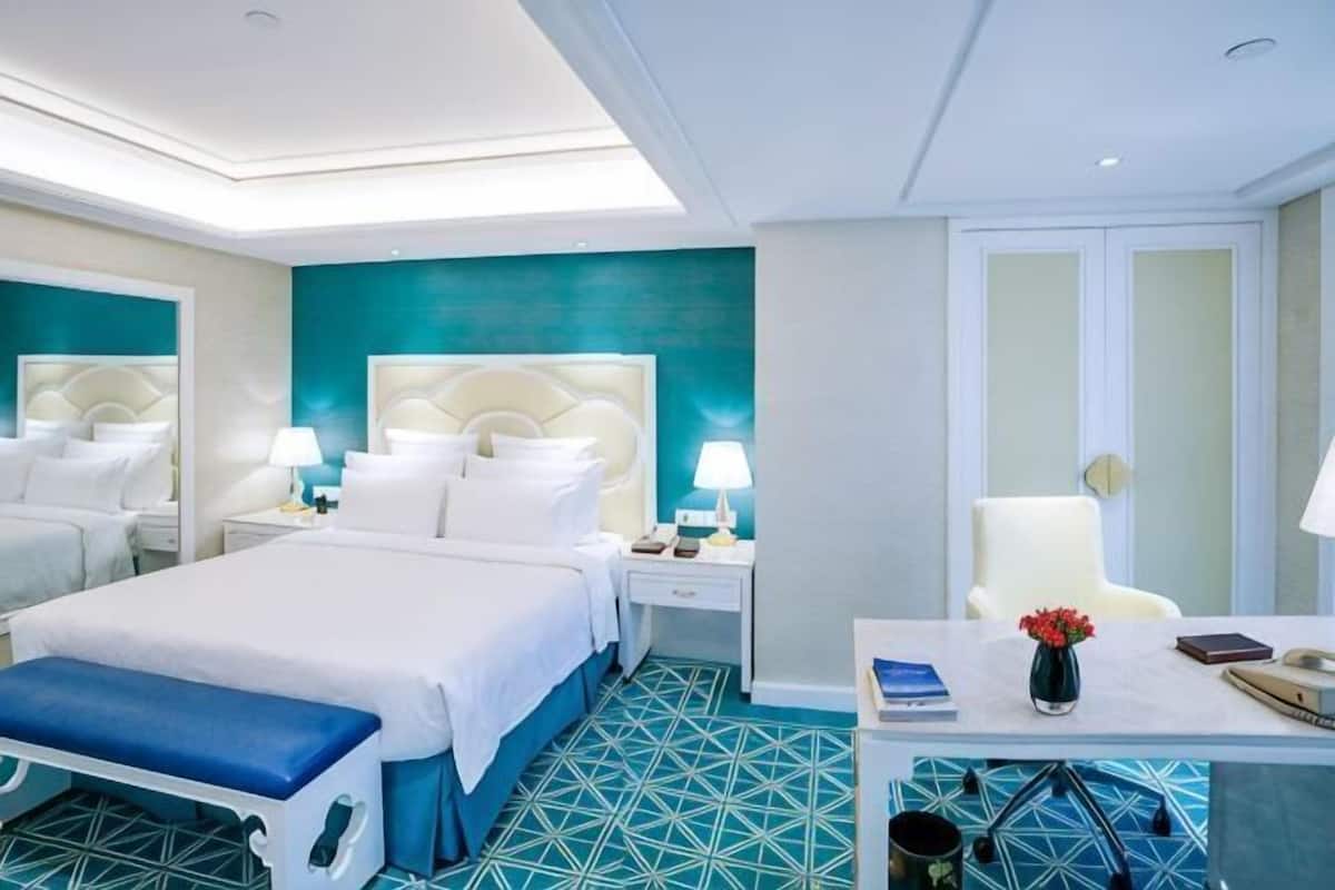 A hotel room with a large bed, bedside tables, a desk, and a chair.
