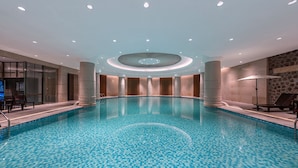 Ein Hallenbad mit Kachelfliesenboden, umgeben von Säulen und einer kreisförmigen Deckenkonstruktion.