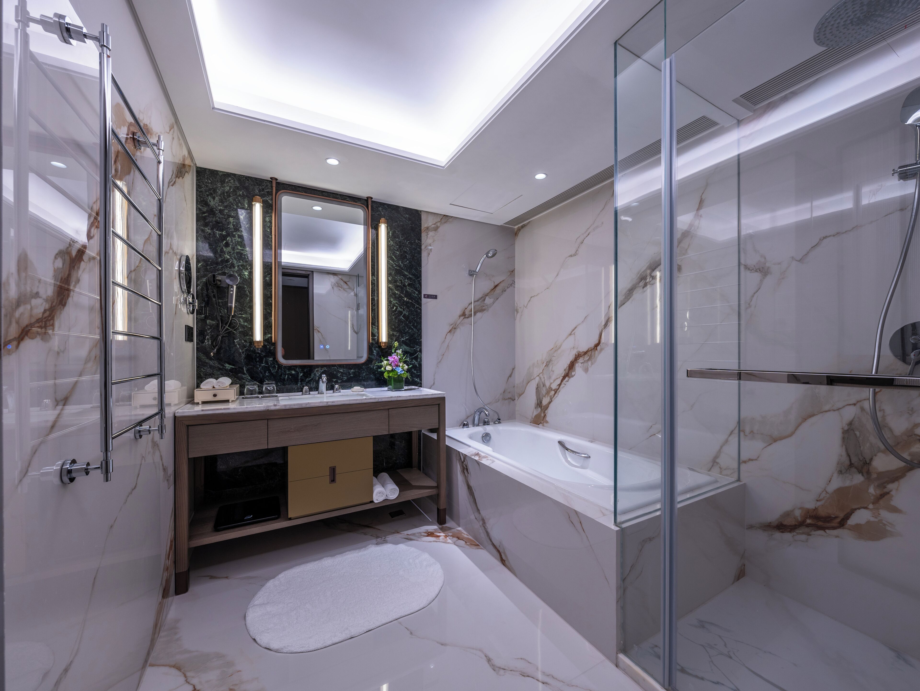 Een moderne badkamer met een glazen douchecabine, een grote spiegel en een vloer van marmer.