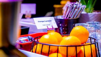 A basket of fresh oranges with a sign reading "Orange à presser" and a metal container with utensils.