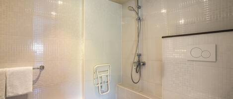 Un baño moderno con ducha a ras de suelo, inodoro y perchero.