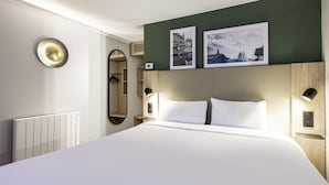 A hotel room with a large bed, a mirror, two framed pictures, a radiator, and a wall-mounted light fixture. - Campanile NATURE - Vierzon (Vierzon)