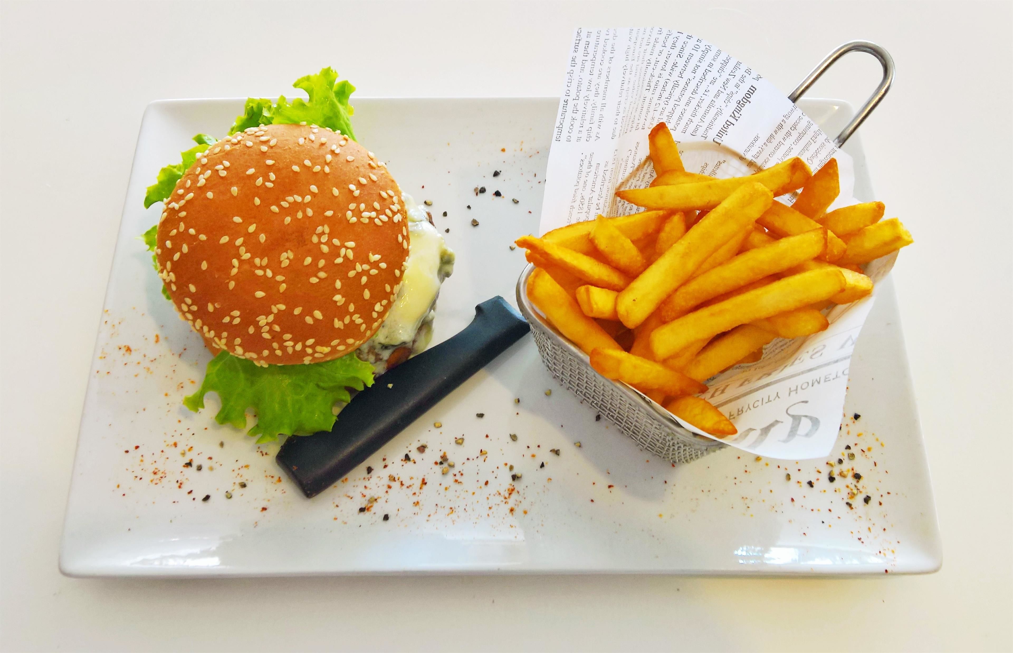 A plate with a hamburger and a basket of French fries.