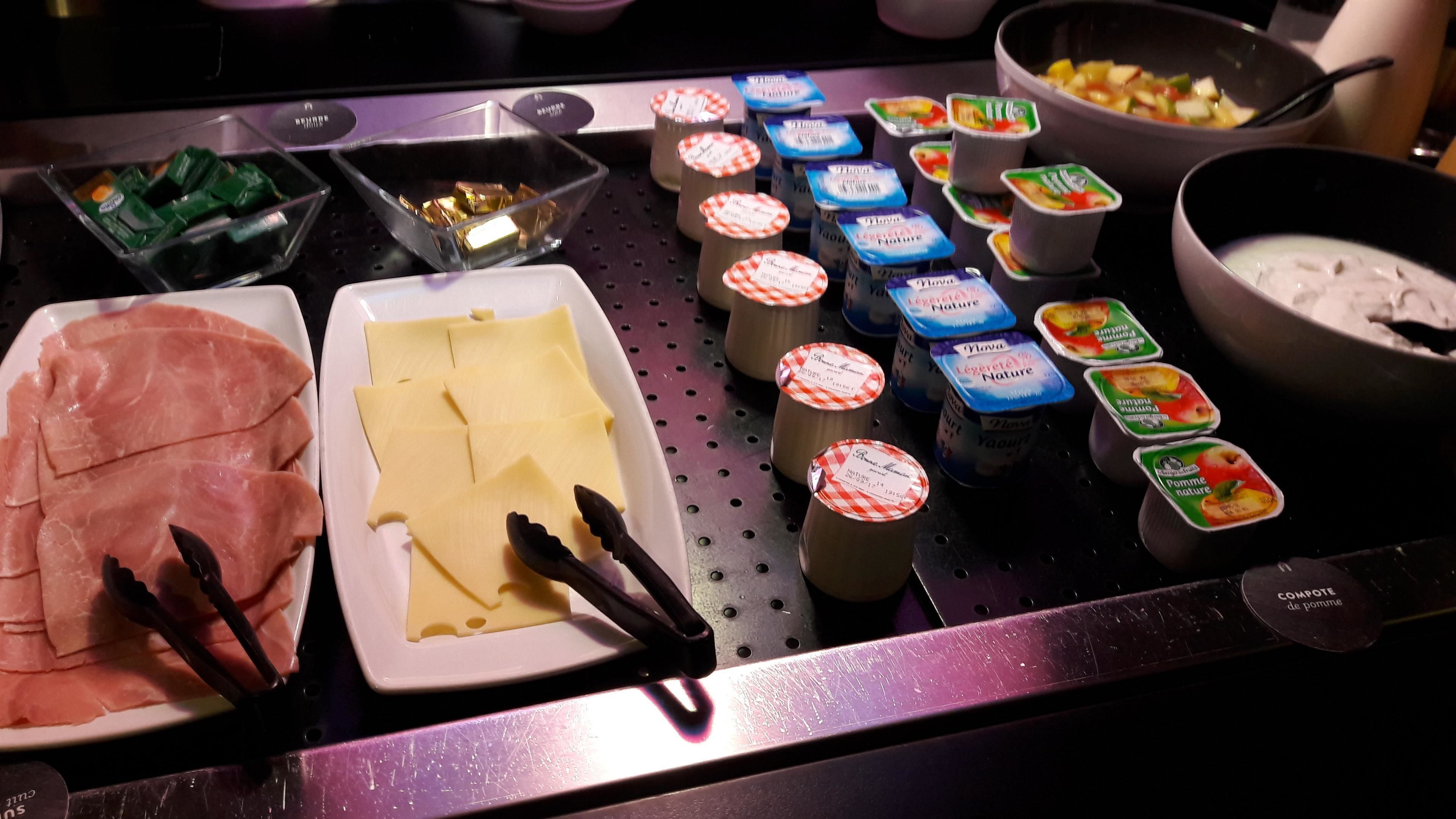 A buffet with various food items including sliced meats, cheese, and yogurt parfaits.