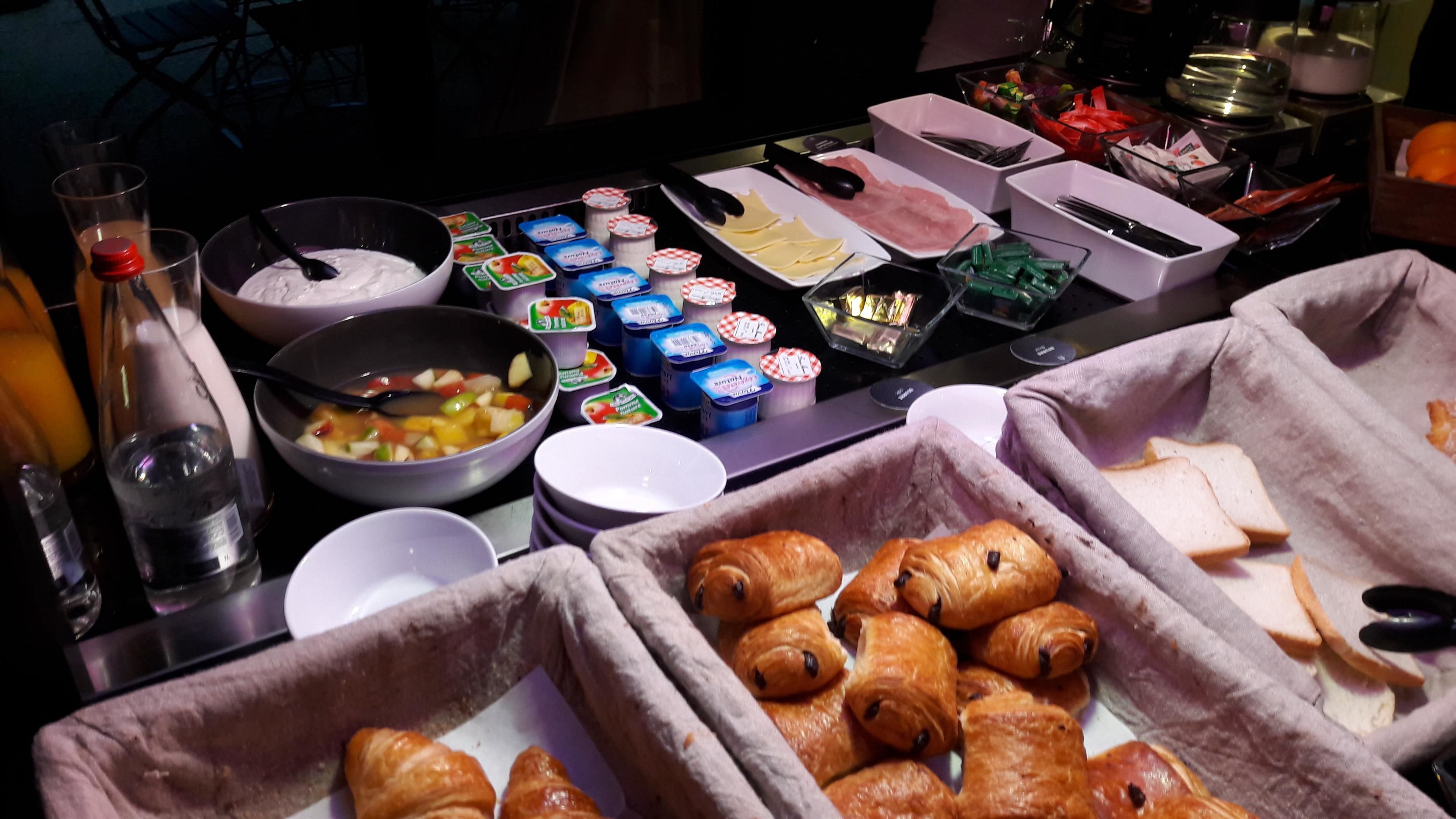 Uma mesa de buffet com diversos alimentos, incluindo croissants, queijo e acompanhamentos.