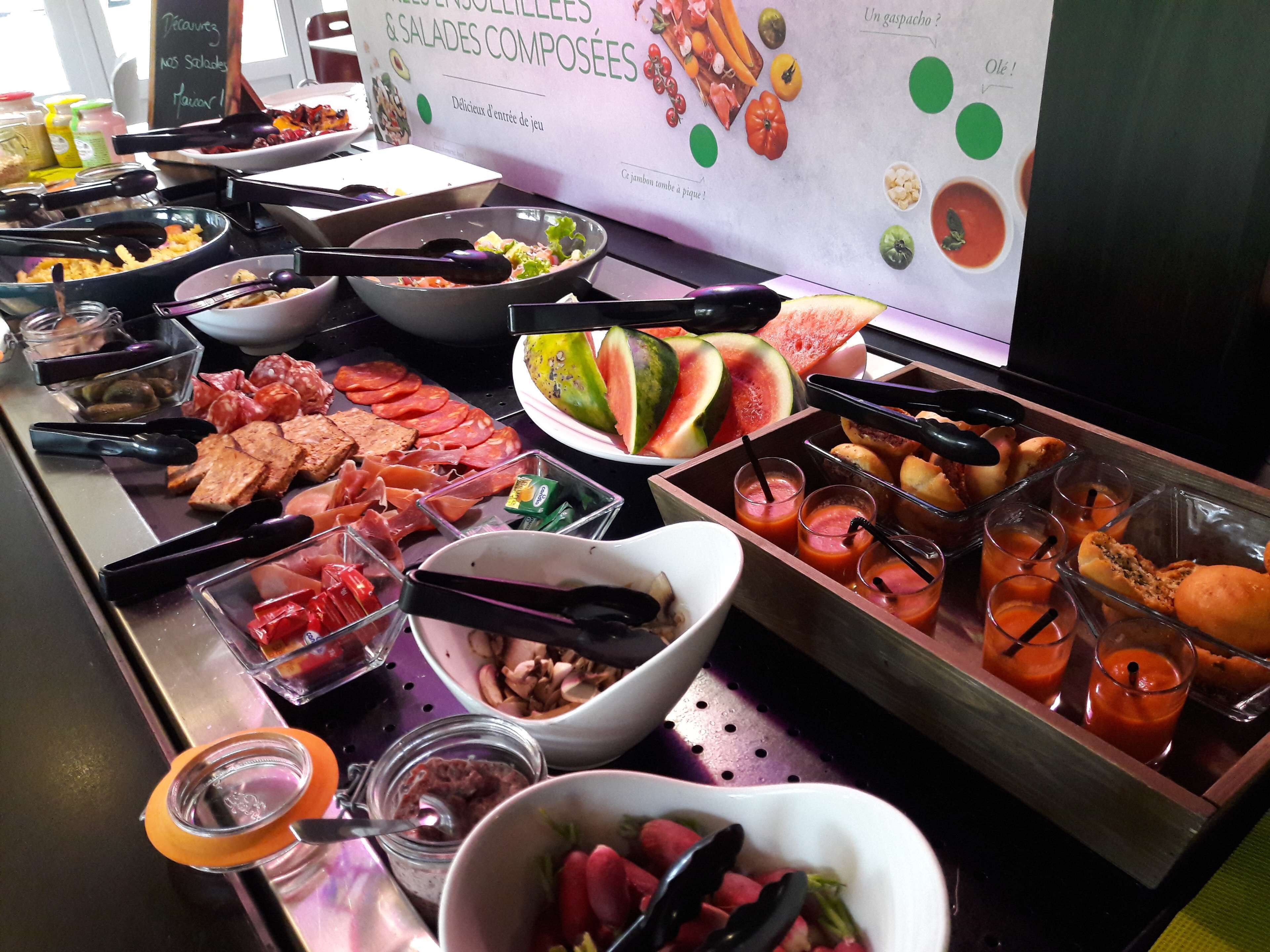 A buffet with various food items including meats, salads, and fruits.
