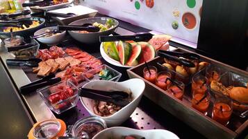 A buffet with various food items including meats, salads, and fruits.