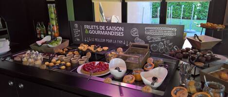 Un bufé con una variedad de frutas, postres y bebidas.