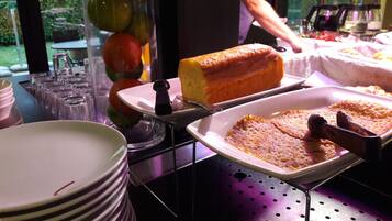A buffet setup with various food items, including a loaf of bread and a dish with a golden-brown crust.