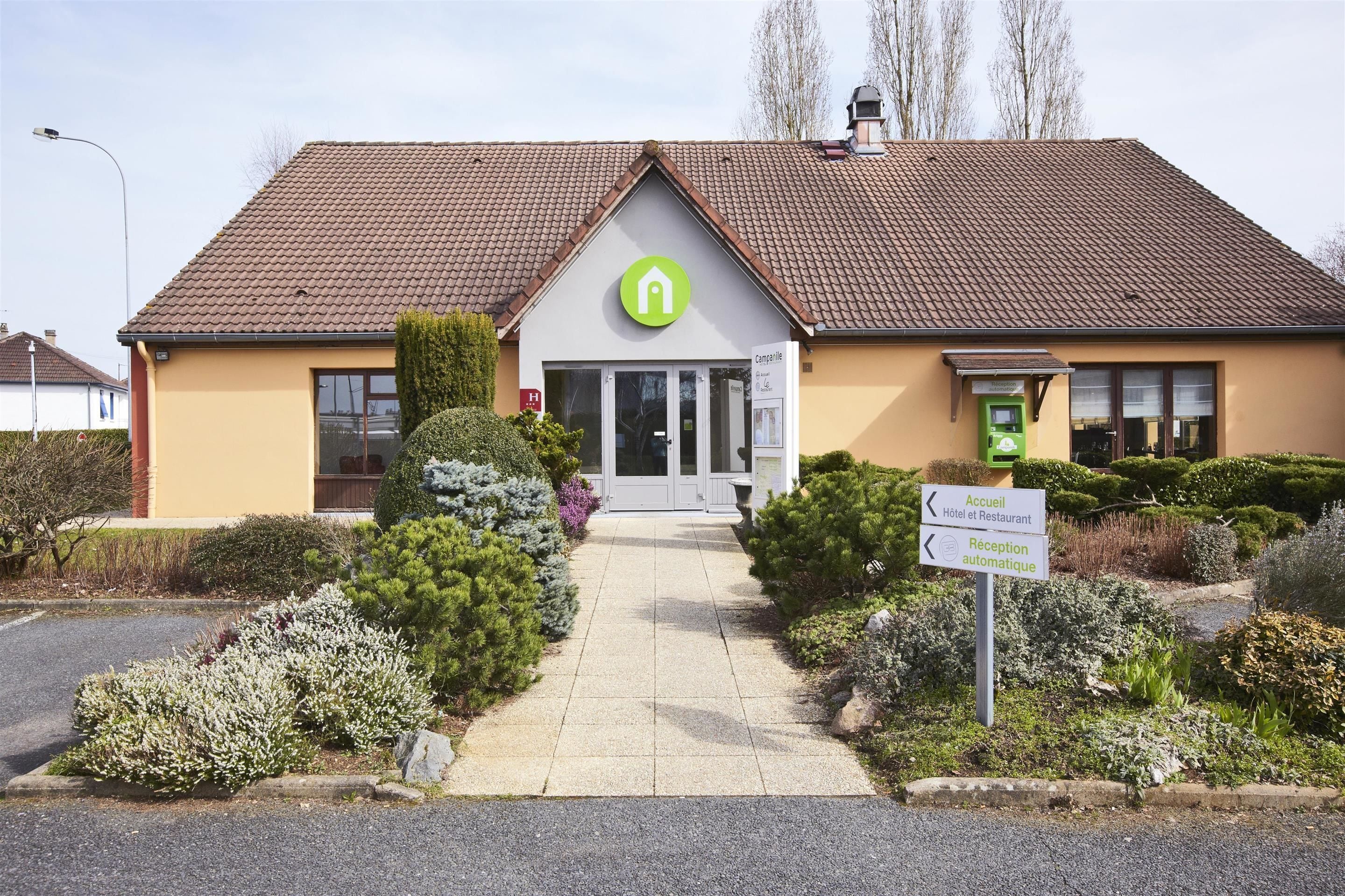 A building with a green logo, a reception desk, and a sign indicating a hotel and restaurant.