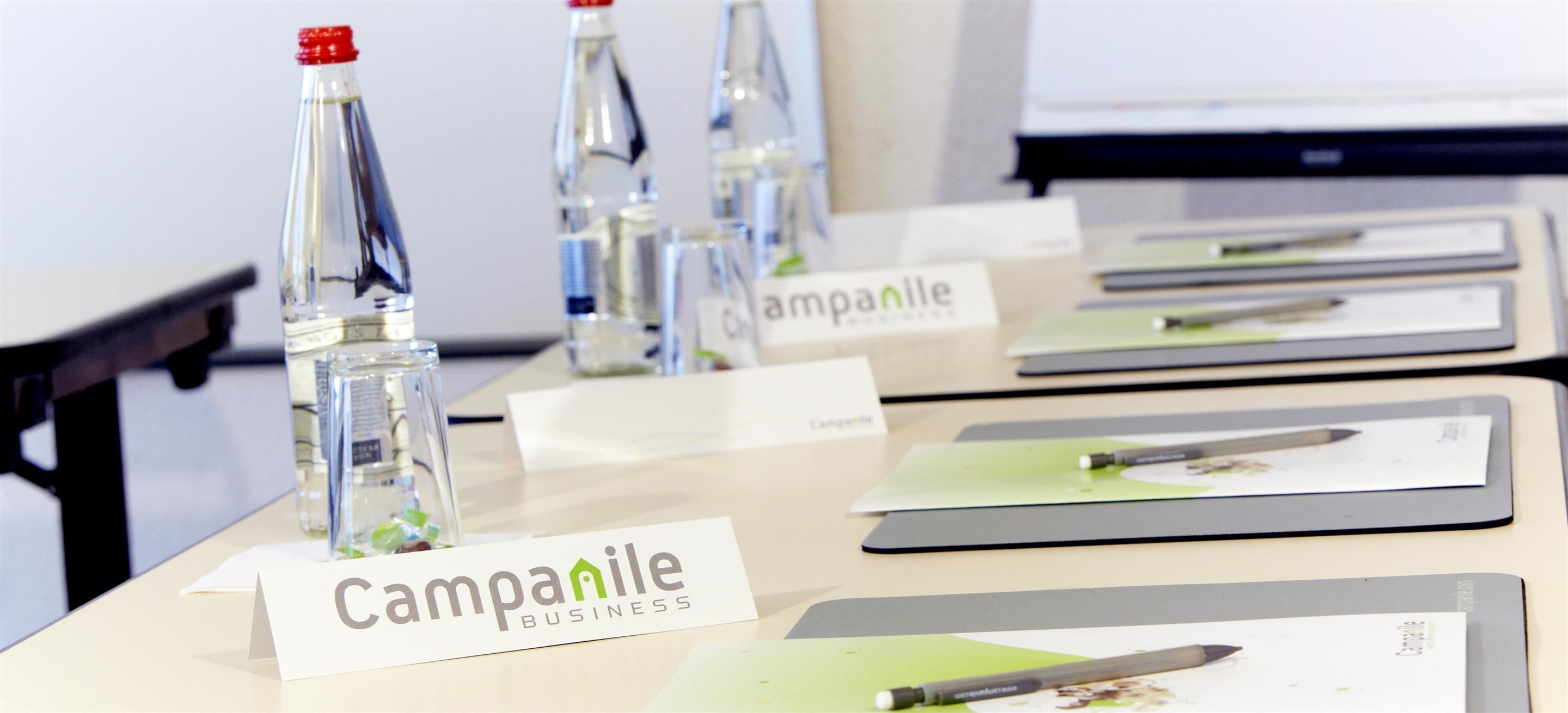 Een vergaderruimte met naamplaatjes met de tekst 'Campanile Business', glazen flessen en naamkaartjes.