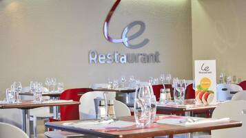 Ein Restaurantinneres mit gedeckten Tischen, einem Menüständer und einem an der Wand befestigten Schild.