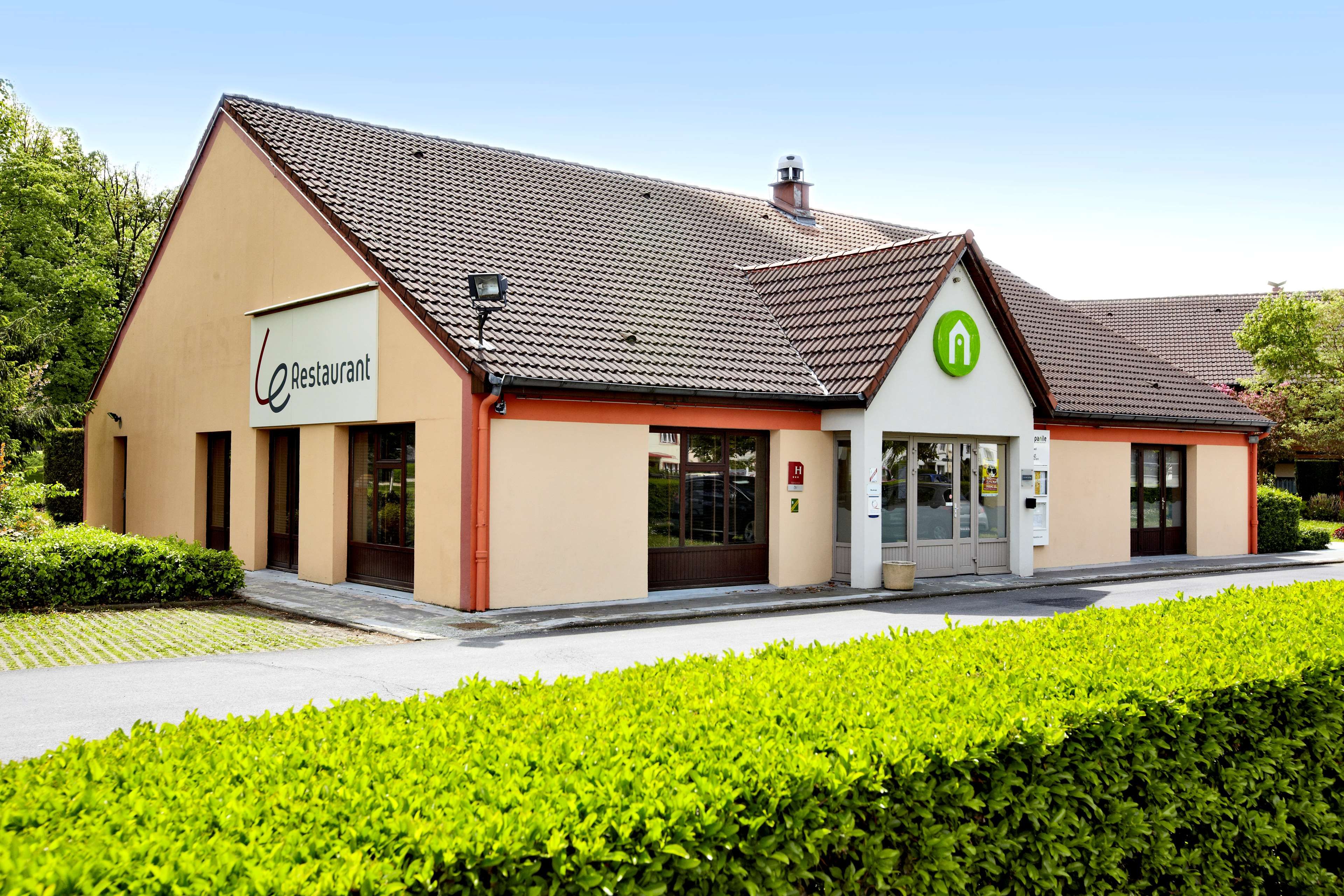 A building with a restaurant sign, a green logo, and a parking sign.