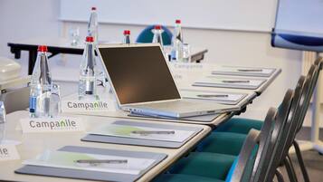 Une salle de conférence avec une longue table, des ordinateurs portables, des plaques nominatives et des bouteilles d’eau.