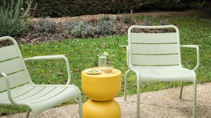 Two white metal chairs with green stripes, a yellow round table, and a glass with a lemon slice and a small container on the table. - Campanile NATURE - Thionville Yutz (Yutz)