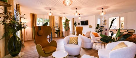 Un salón espacioso con muebles modernos, una mesa de centro redonda y un televisor montado en la pared.