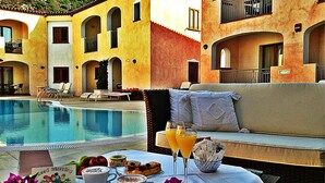 Un coin petit-déjeuner aménagé au bord de la piscine, avec une table, des boissons et un canapé.