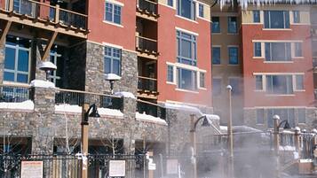 A multi-story hotel with balconies, a pool area with a hot tub, and a stone facade.