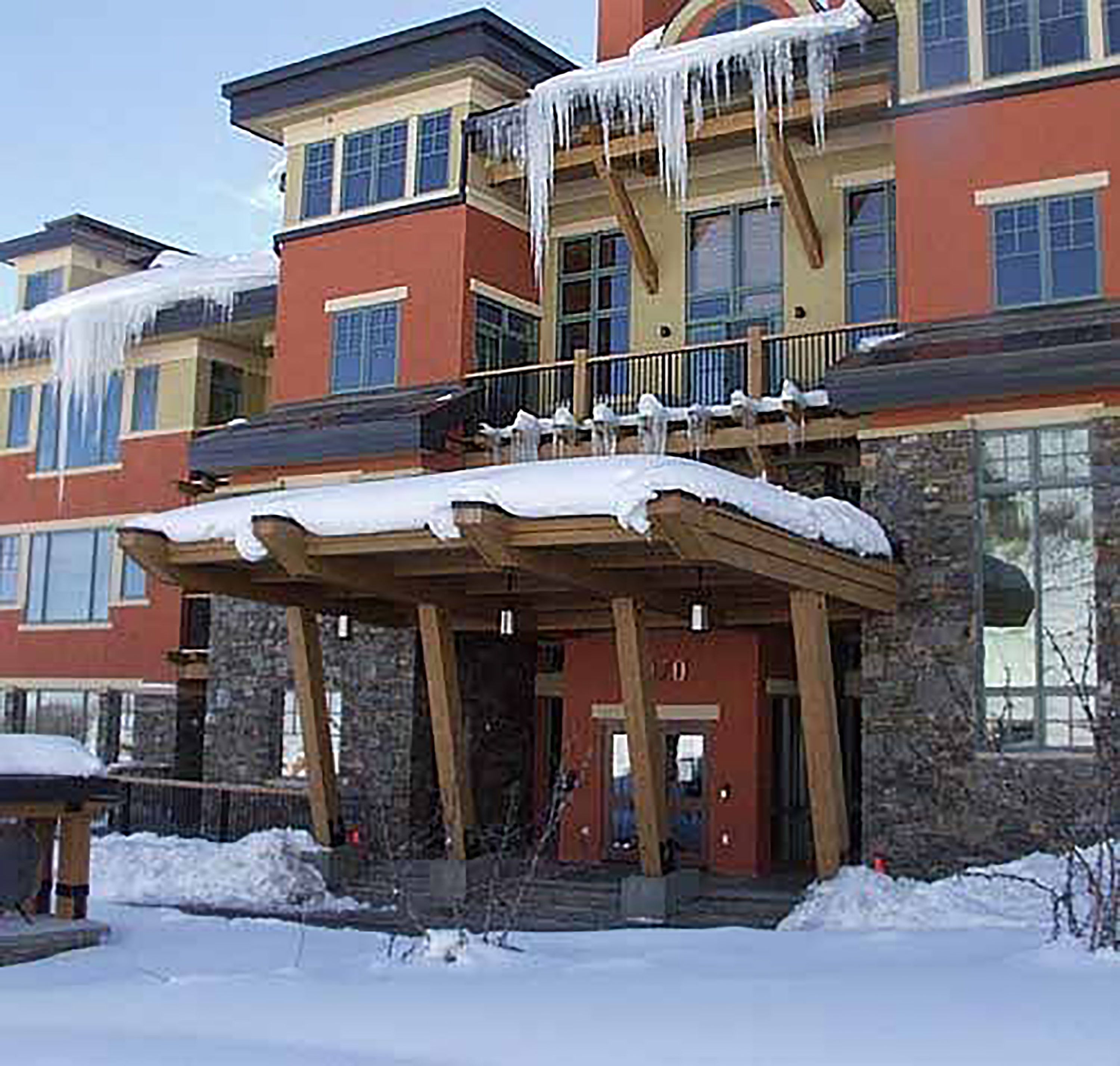 Un edificio de varios pisos con un espacio exterior cubierto y nieve en el suelo.