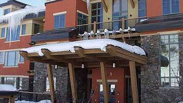 Un edificio de varios pisos con un espacio exterior cubierto y nieve en el suelo.