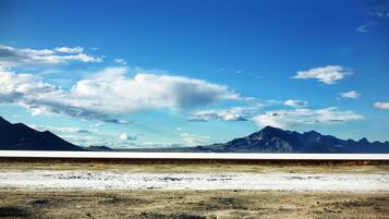 A vast, flat landscape with distant mountains under a clear blue sky.