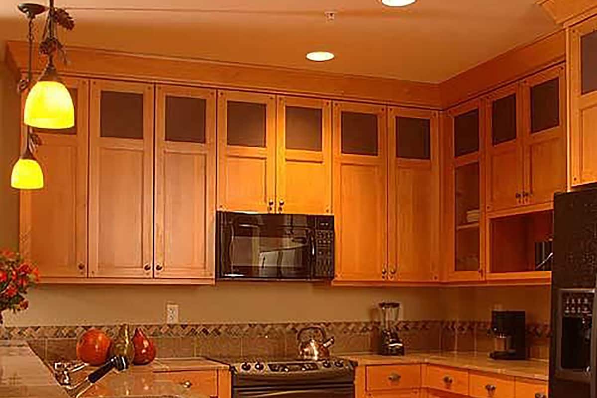 A kitchen with wooden cabinets, a microwave, stove, and refrigerator.