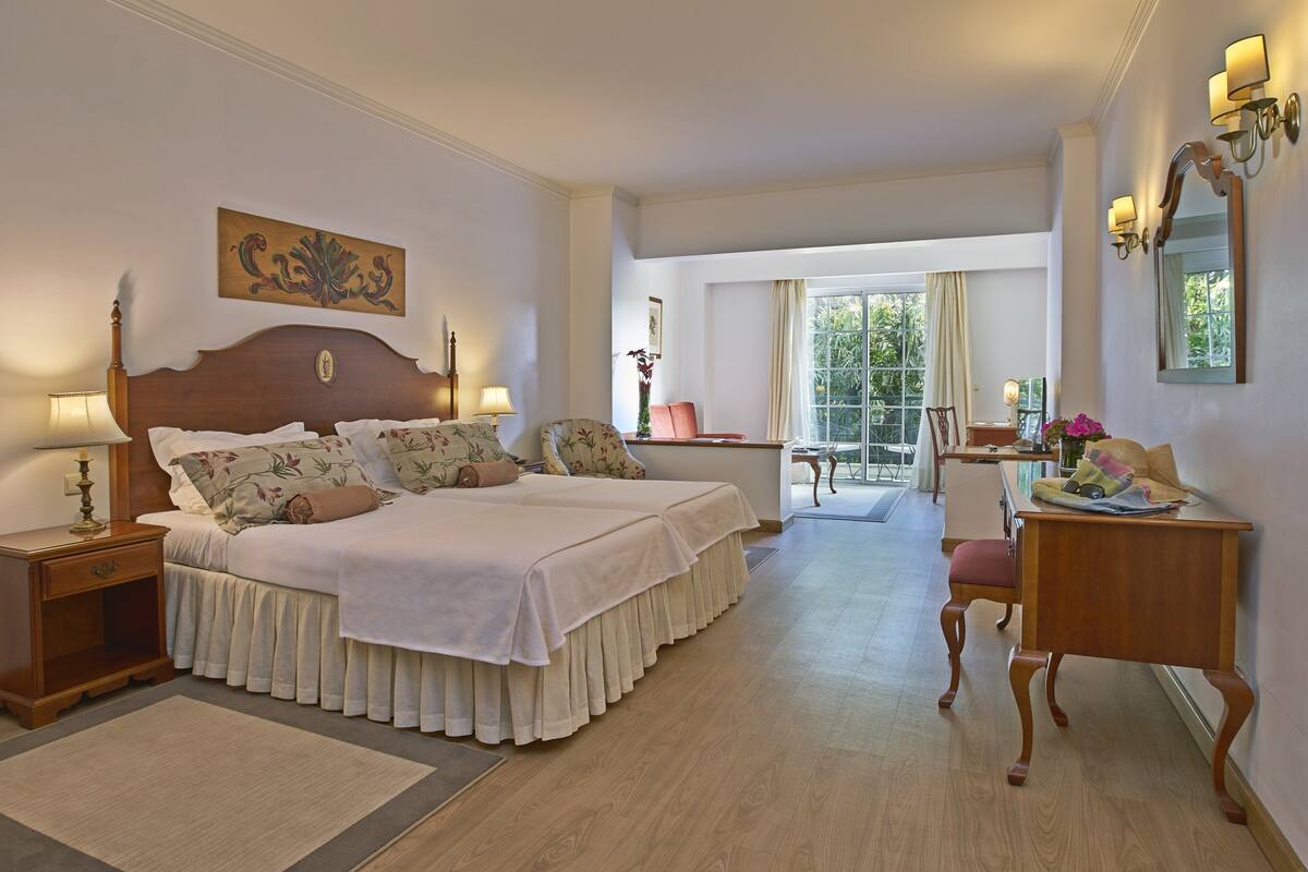Ein Hotelzimmer mit einem großen Bett, Nachttischen, einem Schreibtisch und einem Sessel.