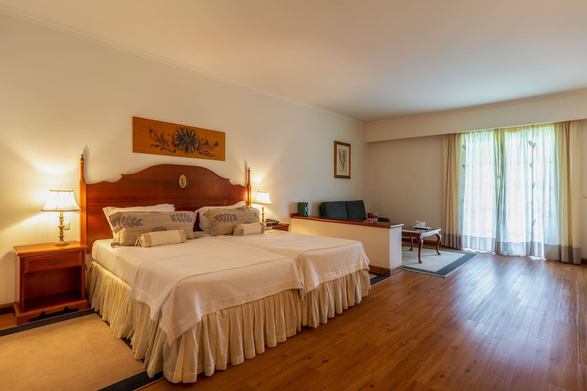 Ein Hotelzimmer mit einem großen Bett, Nachttischen mit Lampen, einem Schreibtisch und einem Sessel.